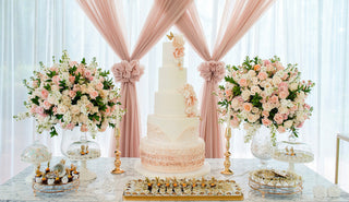 Elegant sweet table decorated with fresh white roses light pink roses and ruscus greenery from Bloomingmore for a wedding or celebration