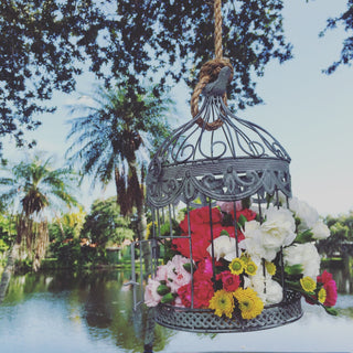 DIY floral birdcage centerpiece made with fresh carnations and pompom buttons from Bloomingmore hanging under a tree for an outdoor dinner