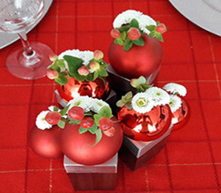DIY Christmas flower ornament centerpiece made with white pompom mums and hypericum berries placed inside hanging ball ornaments on candlesticks as holiday table decor