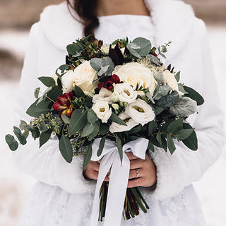 Elegant winter wedding floral arrangement with white roses hydrangeas eucalyptus and greenery as a bridal bouquet and ceremony decor inspiration